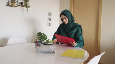 Odaklanmış kadın belgeleri sessiz bir ofis ortamında gözden geçiriyor, organizasyon ve konsantrasyon vurgulanıyor