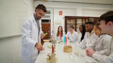 Üniversite profesörü çeşitli öğrenci gruplarına kimya öğretiyor, deneyler yapıyor ve tepkileri açıklıyor.