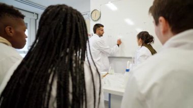 Kimya hocası, ilgili öğrencilere laboratuvar ortamında eğitim etkileşimi ve bağlanmaya odaklanan kavramları anlatıyor.