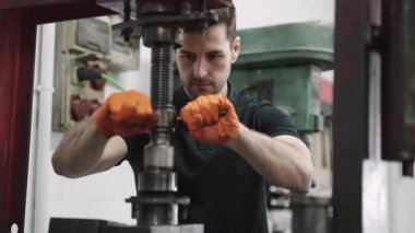 Ağır makinelere sürgüler takan fabrika işçisi ingiliz anahtarı kullanıyor, bakım veya montaj işleri yapıyor