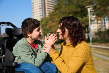 Anne ve oğul, güzel bir sonbahar gününde güneşin tadını çıkararak parkta eğleniyorlar.