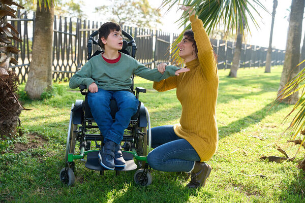 Child with disability enjoying playtime with his therapist in a sunny park, promoting inclusion and rehabilitation