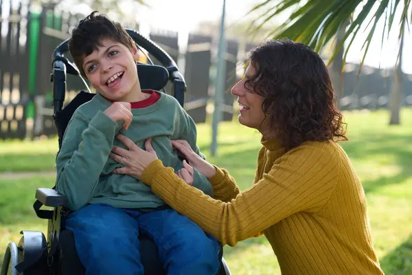 Anne mutlu çocuğuyla oynuyordu. Parkta tekerlekli sandalyede oturuyordu.