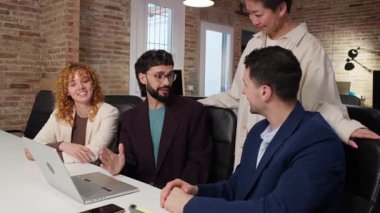 Modern ofis ortamında dizüstü bilgisayar kullanarak bir projede işbirliği yapan iş ekibi. Yavaş çekim onların etkileşimini vurgular.