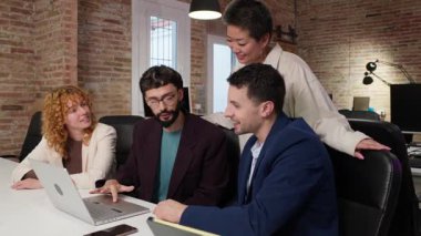 İş adamları bir dizüstü bilgisayar kullanarak modern ofis ortamında takım çalışması ve işbirliği sergileyerek bir proje üzerinde çalışıyorlar. Yavaş çekim