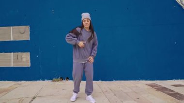 Yetenekli bayan dansçı çeşitli hip hop hareketleri sergiliyor dinamik bir performansla canlı mavi arka plana karşı