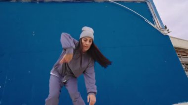 Enerjik hip hop dansçısı canlı bir mavi duvara karşı çeşitli hareketler sergiliyor. Yeteneğini ve dans tutkusunu sergiliyor.