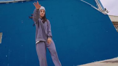 Enerjik bayan dansçı çeşitli hip hop hareketleri sergiliyor canlı mavi arka plana karşı dinamik bir performans içinde