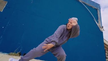 Dinamik hip hop hareketleri sergiliyor. Enerjiyi ve ritmi ifade eden canlı bir mavi arkaplan.