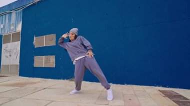 Yetenekli hip hop dansçıları canlı bir mavi duvara karşı dinamik bir performans sergiliyorlar.