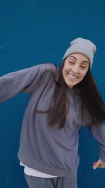Değişik hip hop dans figürleri sergileyen genç bir kadın ve canlı mavi bir arkaplan karşısında ifadeler