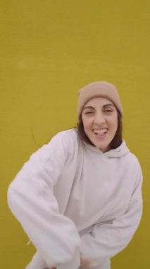 Enerjik hip hop dansçısı etkileyici hareketler yapıyor ve canlı sarı stüdyo arkaplanına karşı neşeli pozlar veriyor, dinamik kentsel dans kişiliği sergiliyor.