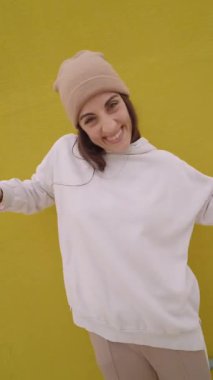 Hip hop dansçısı dinamik hareketler yapıyor ve canlı sarı arkaplan karşısında çarpıcı pozlar veriyor, kentsel dans enerjisini ve bireysel tarzı somutlaştırıyor.