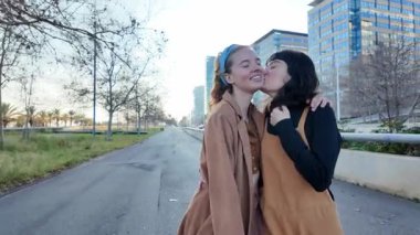 Birbirine aşık iki kadın parkta romantik bir yürüyüşün tadını çıkarırlar, sevgilerini sarılma ve öpücüklerle ifade ederler.