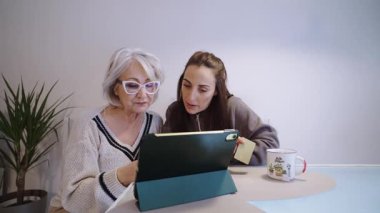 Dijital teknoloji ile çok nesilli bir bağ kurmak, olgun bir kadının destekleyici yetişkin kızıyla çevrimiçi beceriler öğrenmesi rahat ev ortamında.