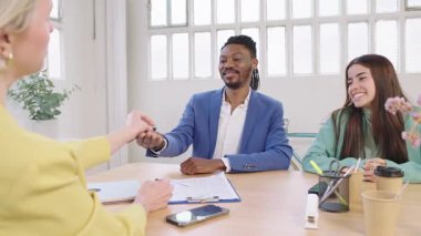 Gayrimenkul uzmanı heyecanlı çiftin mülkiyet anahtarlarını veriyor, başarılı ev alımını ve modern ofis ortamındaki gelecek yaşam tarzını simgeliyor.