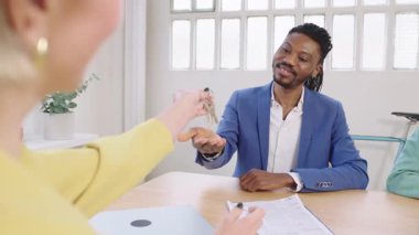 İş adamları başarılı bir anlaşma yaptılar. Anahtarları değiş tokuş edip yavaş çekimde el sıkışıyorlar.