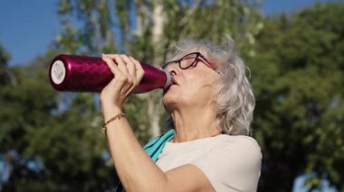 Sunbae, dışarıda park egzersizi sırasında alnından ter silerken susuz kalan yaşlı kadın güneş ışığı altında aktif yaşlanma sağlığını açığa çıkarıyor.