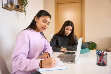 İki genç girişimci evlerinde çalışıyor, harcamaları hesaplıyor ve notlar alıyorlar.