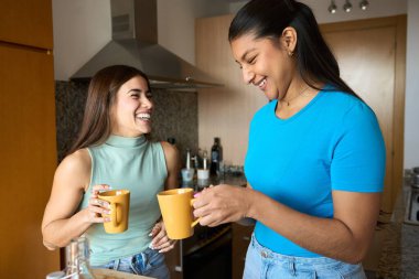 İki ev arkadaşı rahatlatıcı bir sabah geçiriyorlar, kahkahalarla kahkahalar atıyorlar ve mutfaklarında kahve içiyorlar.