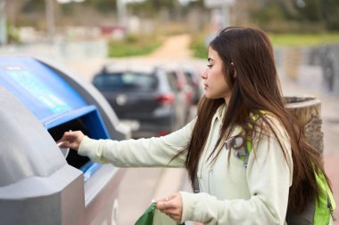 Sorumlu yürüyüşçü, belirlenmiş bir geri dönüşüm kutusuna plastik atıkları atarak çevresel farkındalığı ve sürdürülebilir uygulamaları teşvik ediyor