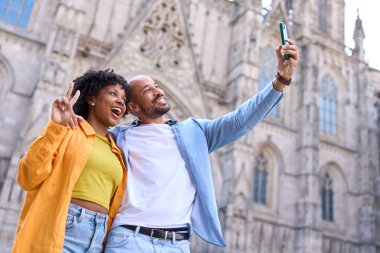 İspanya 'da yaz tatilinde Barselona Katedrali önünde akıllı telefonlu selfie çeken mutlu turistler.