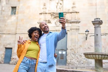 Mutlu turistler Barselona, İspanya 'da akıllı telefonlarıyla selfie çekiyorlar. Santa Felipe Neri yakınlarında yaz tatillerinin tadını çıkarıyorlar.