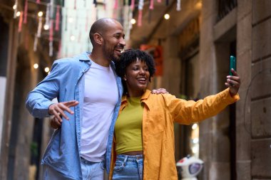 Barselona, İspanya 'da güzel dekore edilmiş dar bir sokakta yürürken selfie çeken mutlu turistler neşe ve beraberlik saçıyor.