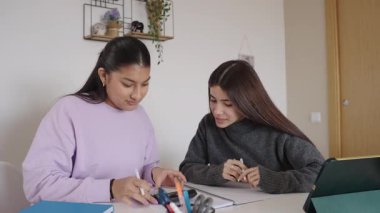 Akademik ödevde birlikte çalışan kız öğrenciler, masadaki odaklanmış konsantrasyonlu işbirlikçi öğrenme için dijital araçlar kullanıyorlar