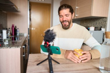Sosyal medya için çevrimiçi içerik oluşturan, bir vlog kaydeden ve mutfağında bir fincan kahvenin keyfini çıkaran bir etken