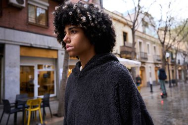 Kendine güvenen genç bir kız öğrenci, siyah bir kapüşonlu giyip, şehir yaşam tarzını ve genel z modasını sergiliyor.