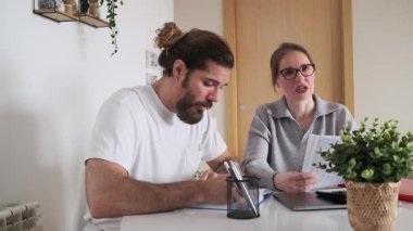 Kadın ve erkek, iç hesapları inceliyor ve evdeki faturalar ve harcamalar hakkında sohbet ediyorlar.