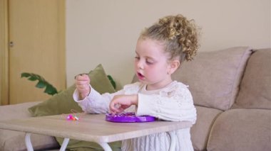 Genç kız renkli boncukları dikkatlice diziyor, evde yaratıcı işçilik yaparken el yapımı bilezik tasarlarken konsantre oluyor.