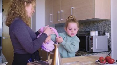 Genç aşçılık becerilerini geliştirmek, şefkatli bir annenin kızına mutfak ortamında birlikte yemek pişirmeden önce önlük giydirmesi.