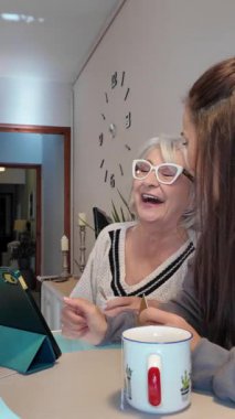 Yaşlı kadın kızıyla origami dersinden zevk alıyor, neşe ve odak ile kağıt şekiller yaratıyor.