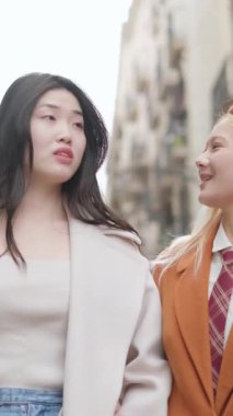 Ağır çekimde birlikte yürüyen ve konuşan genç kadınlar, gündüz saatlerinde şehir caddesinde samimi bir bağ ve arkadaşlık paylaşıyorlar.