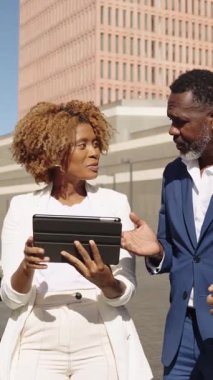 Profesyonel iş ekibi tablet stratejisini tartışıyor, kendine güvenen şehir planıyla ağır çekimde işbirliği yapıyor.