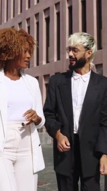 Proje detaylarını güneşli gündüz vakti cam ve çelik şirket merkezinin önünde yürüyen ve tartışan iş adamları.