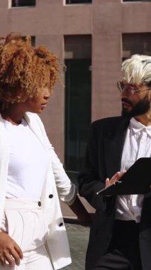 İki iş arkadaşı bir tablet üzerinde bir projeyi inceliyor, açık havada verimli bir tartışmaya giriyorlar.