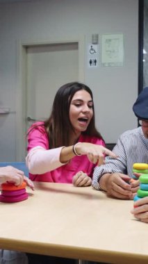 Genç doktor yaşlı bir adama renkli yüzükleri istiflemede yardımcı oluyor, yavaş çekimde hareket becerileri geliştiriyor.