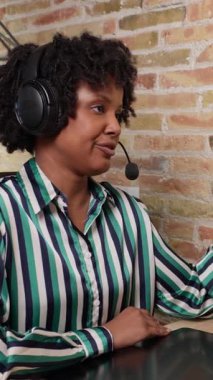 Dost canlısı bayan müşteri hizmetleri temsilcisi kulaklık takıyor ve müşteriye yavaş çekimde yardımcı oluyor.