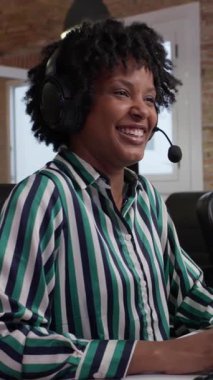 Güvenilir kadın müşteri hizmetleri temsilcisi kulaklık takarken sıcak bir şekilde iletişim kuruyor, modern ofis ortamında profesyonel olarak çalışıyor.