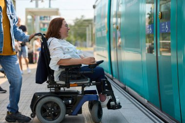 Engelli insanların tekerlekli sandalyesini iten bakıcı erişilebilir tramvay