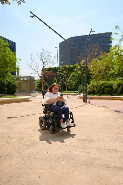 Engelli mutlu kadın şehir parkında sosyal medyada geziniyor.