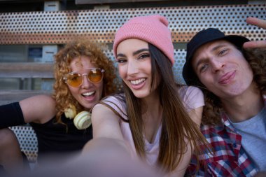 Üç neşeli arkadaş birlikte bir anın tadını çıkarıyor, neşeli gülümsemelerini ve arkadaşlığın özünü canlı bir selfie 'de yakalıyorlar.