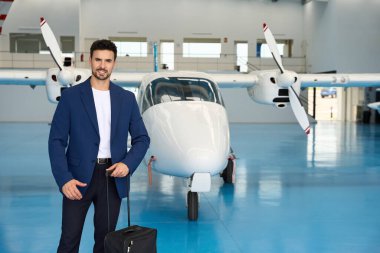 İş adamı özel bir uçağın önünde özel bir çanta tutuyor. İş gezisine hazırlanıyor.