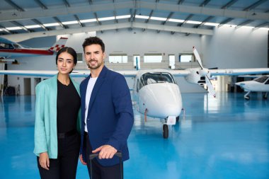 Geleceğin pilotları, uçak hangarında küçük bir pervane uçağının yanında gururla duruyor. Uçma ve macera özlemlerini somutlaştırıyorlar.