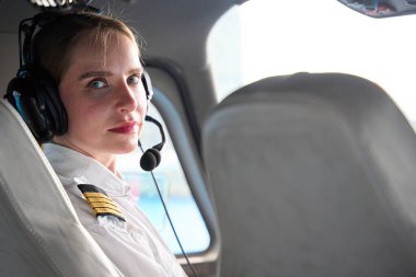 Bir uçak kokpitinde oturan, kulaklık takan genç bir kadın pilot, yaklaşan bir uçuş için özgüvenle hazırlanmaya odaklandı.