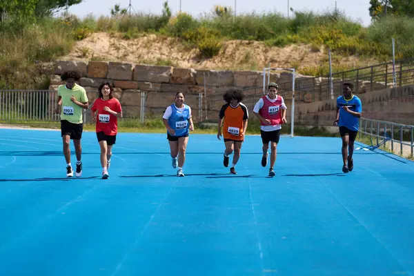 Canlı mavi bir pistte yarışan altı genç sporcu yarışmayla dolu heyecanlı bir yarışta hızlarını ve kararlılıklarını sergiliyorlar.