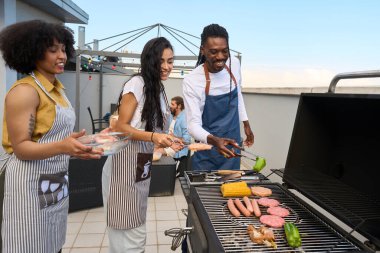 Şefler canlı bir barbekü partisinde leziz et ve taze sebzeler pişiriyor arkadaşlarıyla yaz güneşinin tadını çıkarıyorlar.